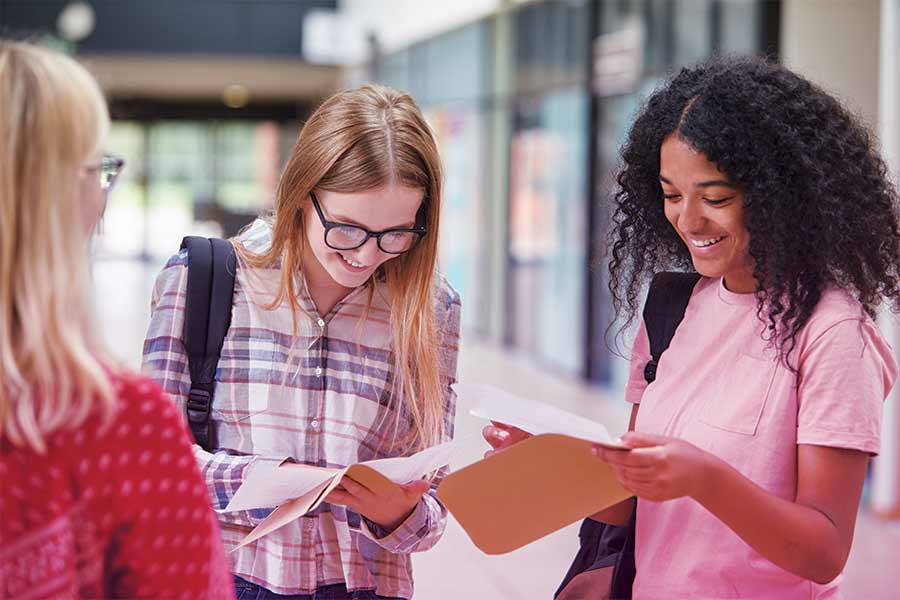 Two girls receiving their results on GCSE results day looking happy